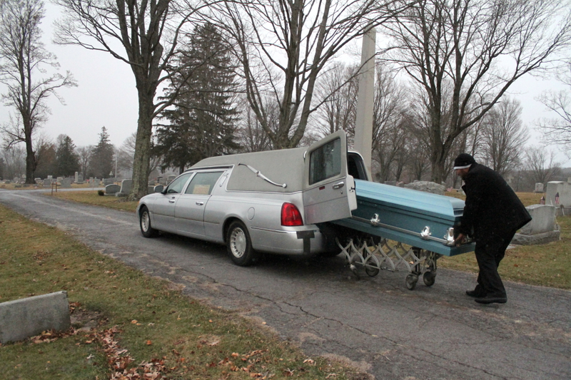 Unloading the casket onto the church truck.
